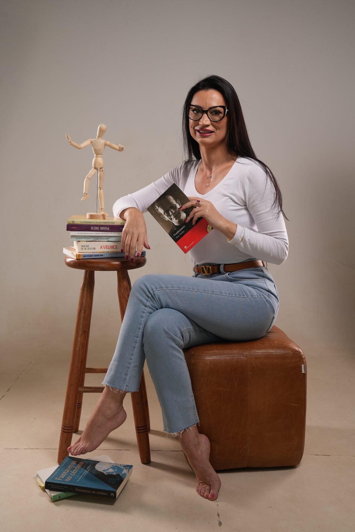 Dra. Juliana Gai com livros de neurociência e um manequim articulado
